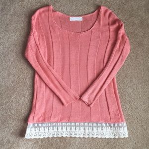 Coral sweater with lace trim hem.